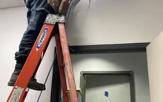 Electrician installing ceiling wiring as part of International Banking Company interior upgrades.