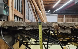 Close-up of exposed concrete slab and electrical wiring during demolition and structural prep for specialty retail construction project