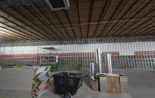 Metal stud framing in progress for new retail interior walls with drywall stacked and ready for installation