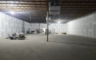 Drywall installation nearing completion with finished walls and mechanical systems in place during retail construction project