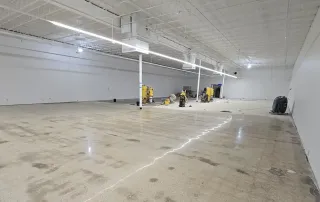 Polished concrete floor installation in progress inside large retail space with equipment staged for finishing