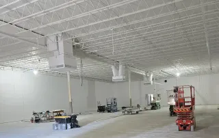 Interior view of retail renovation showing painted white ceiling, ductwork, and construction equipment during build-out
