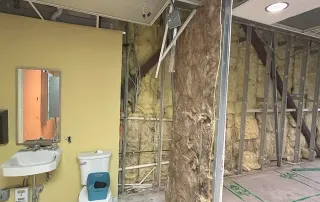 Restroom under construction – Rough-in plumbing, framing, and wall insulation work during build-out phase.