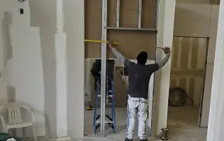 Construction worker measuring framing during Palm Beach Tan retail construction remodel by Omega Contracting & Consulting
