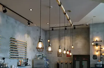 Industrial retail space lighting with track lights and accent pendant fixtures over a counter.